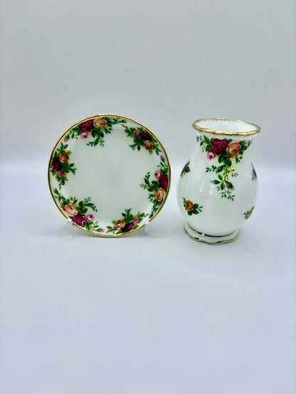Small white vase and plate with floral patterns on a light gray background