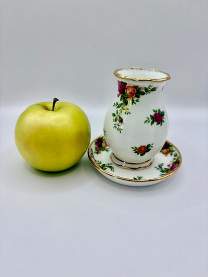 Decorative floral teacup and saucer with a green apple on a white background