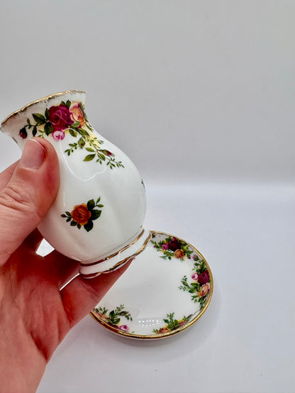 Decorative teacup with floral patterns held by a hand on a light gray background