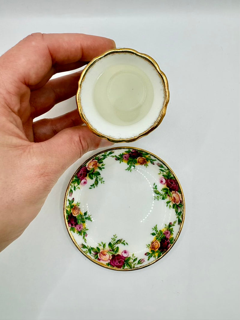 Hand holding a decorative ceramic plate with floral design on a plain background