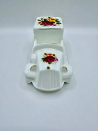 White ceramic miniature toilet with floral design on a white background