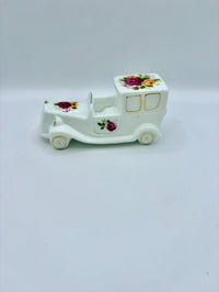 White ceramic toy car with floral designs on a white background