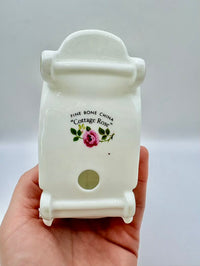 White ceramic product with 'Cottage Rose' branding held in a hand against a light gray background