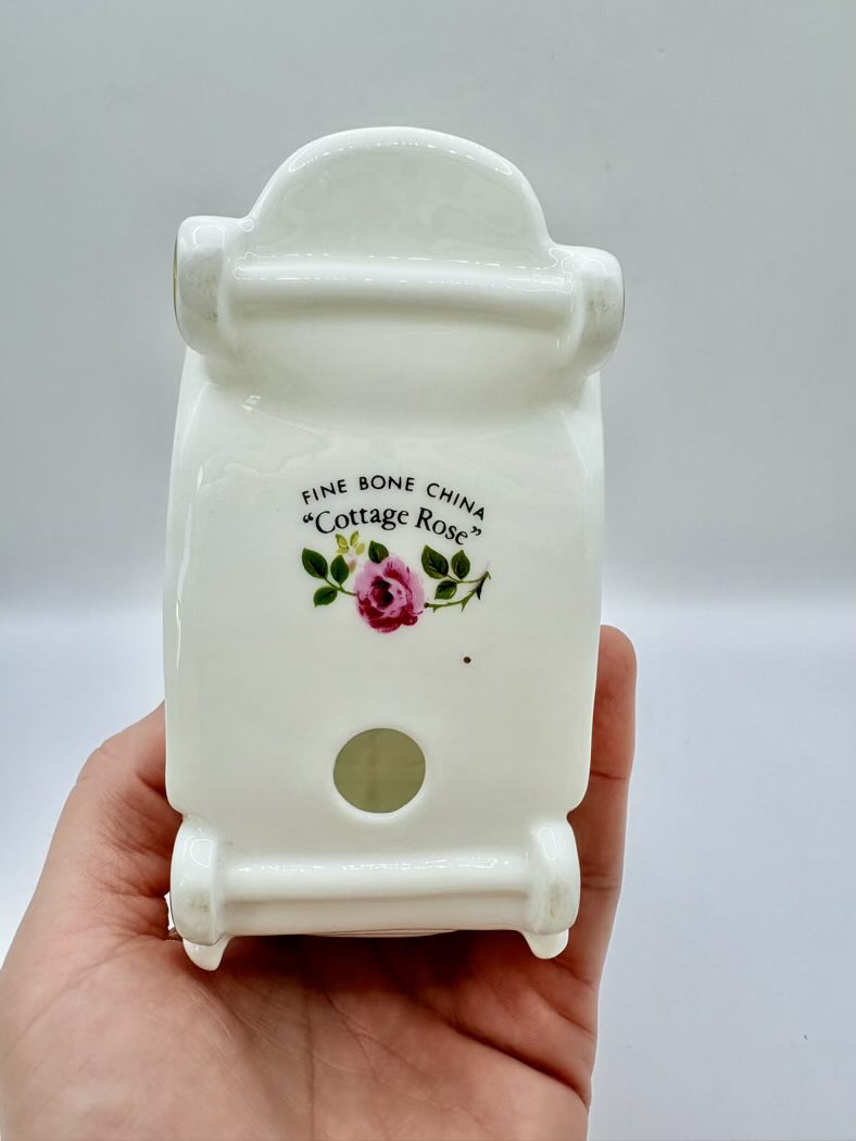 White ceramic product with 'Cottage Rose' branding held in a hand against a light gray background