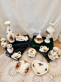 Collection of ceramic tea sets and vases on a lace tablecloth with a neutral background.