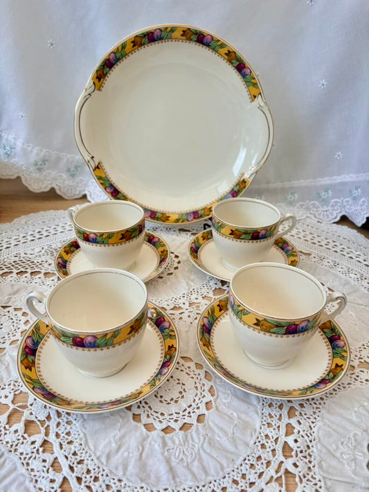 Set of vintage tea cups and saucers with floral patterns on a lace tablecloth.