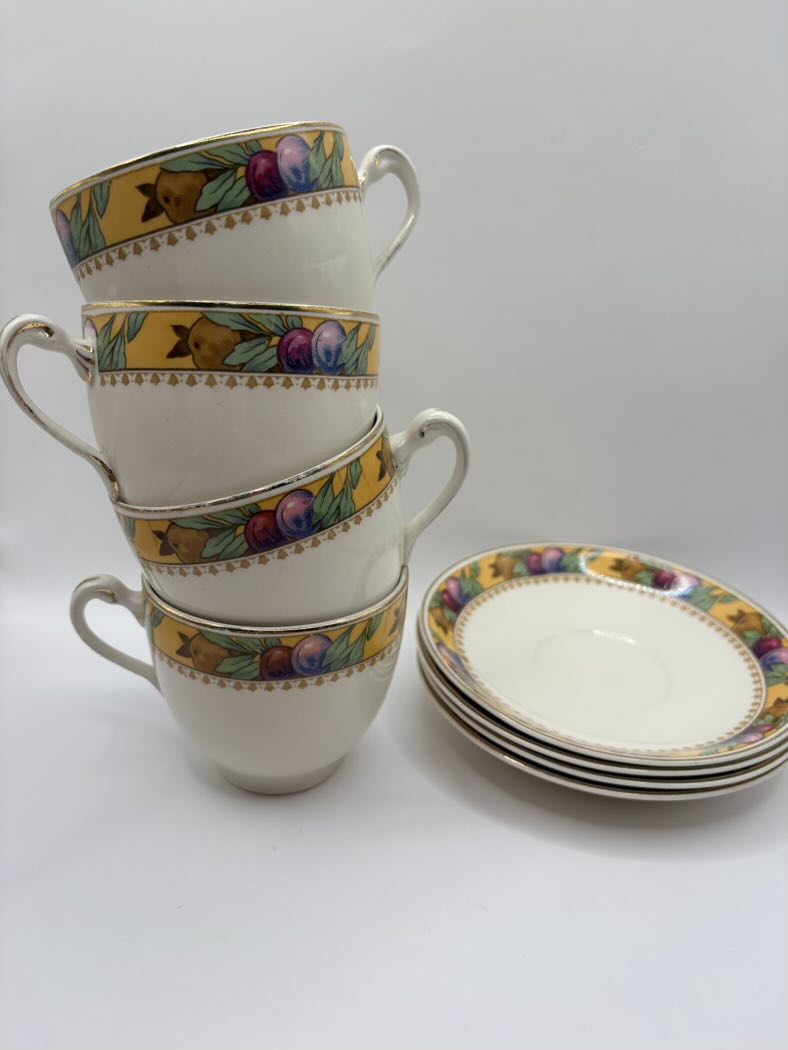 Set of ceramic cups and saucers with decorative borders on a white background