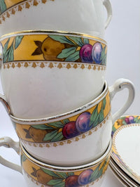 Stack of ceramic teacups with decorative fruit patterns on a white background