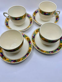 Set of four ceramic teacups and saucers with floral patterns on a white background
