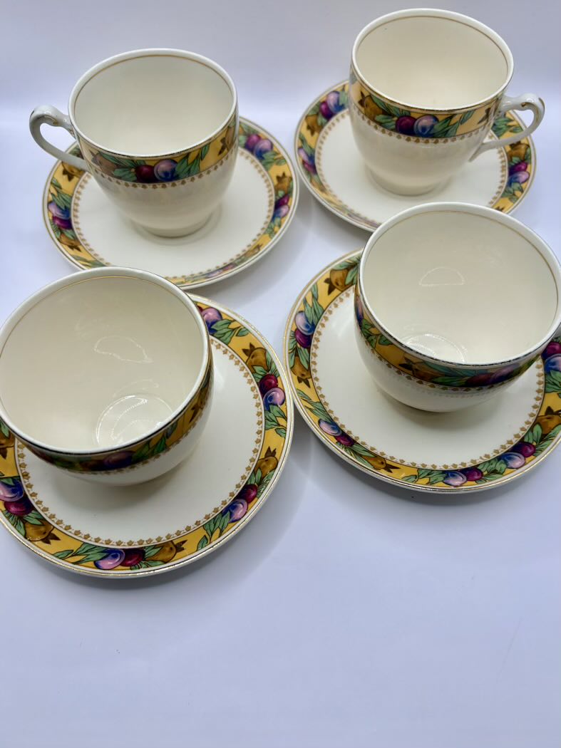 Set of four ceramic teacups and saucers with floral patterns on a white background