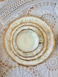 Stack of ceramic plates with gold trim on a lace tablecloth