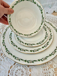 Stack of decorative plates with green floral patterns on a lace tablecloth