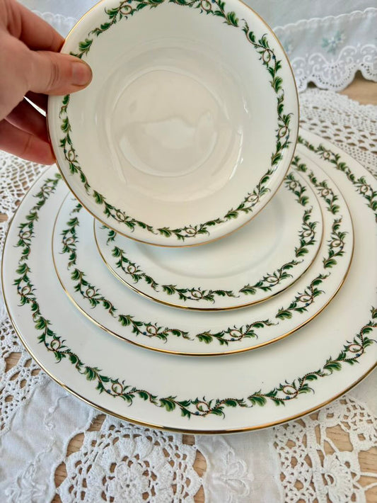Stack of decorative plates with green floral patterns on a lace tablecloth