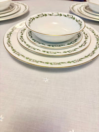 Set of ceramic dinnerware with decorative edge on a light gray surface