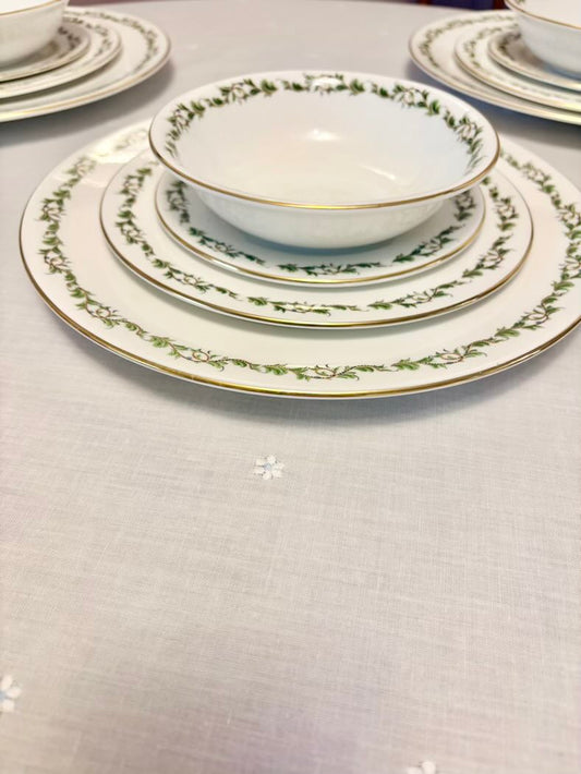 Set of ceramic dinnerware with decorative edge on a light gray surface