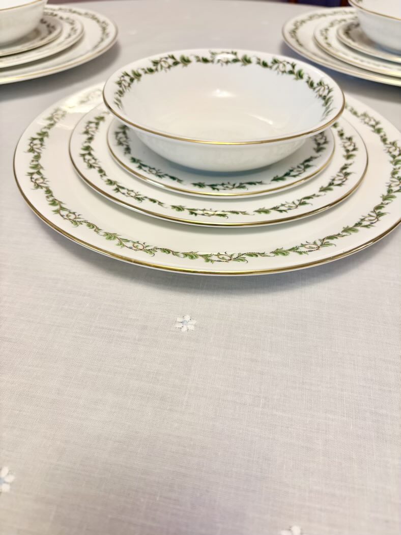 Set of ceramic dinnerware with decorative edge on a light gray surface