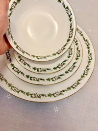 Set of stacked ceramic plates with decorative green patterns on a light gray background