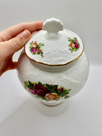 White ceramic jar with floral designs on a white background