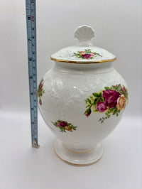 Decorative ceramic jar with floral designs and a measuring tape for scale on a white background