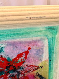 Close-up of a textured surface with colorful abstract art and wooden frame.