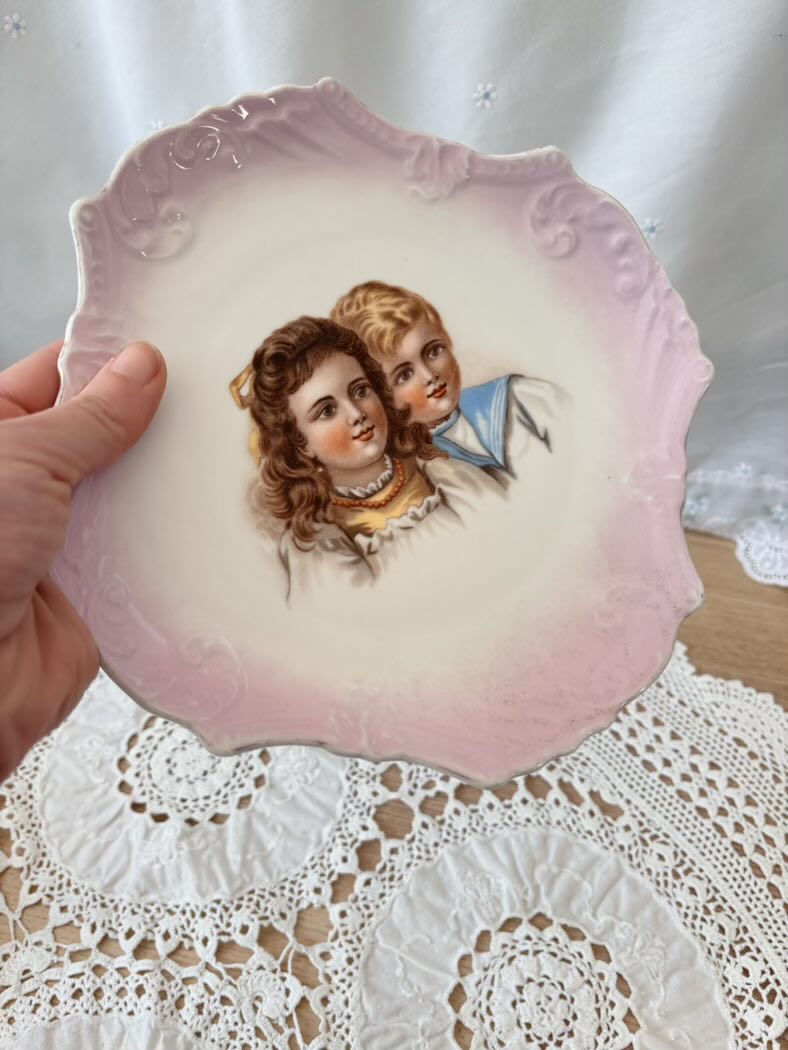 Decorative plate with an illustration of two children on a lace doily