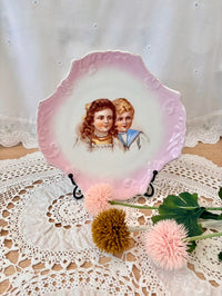 Decorative plate with a vintage illustration of two children on a lace doily.
