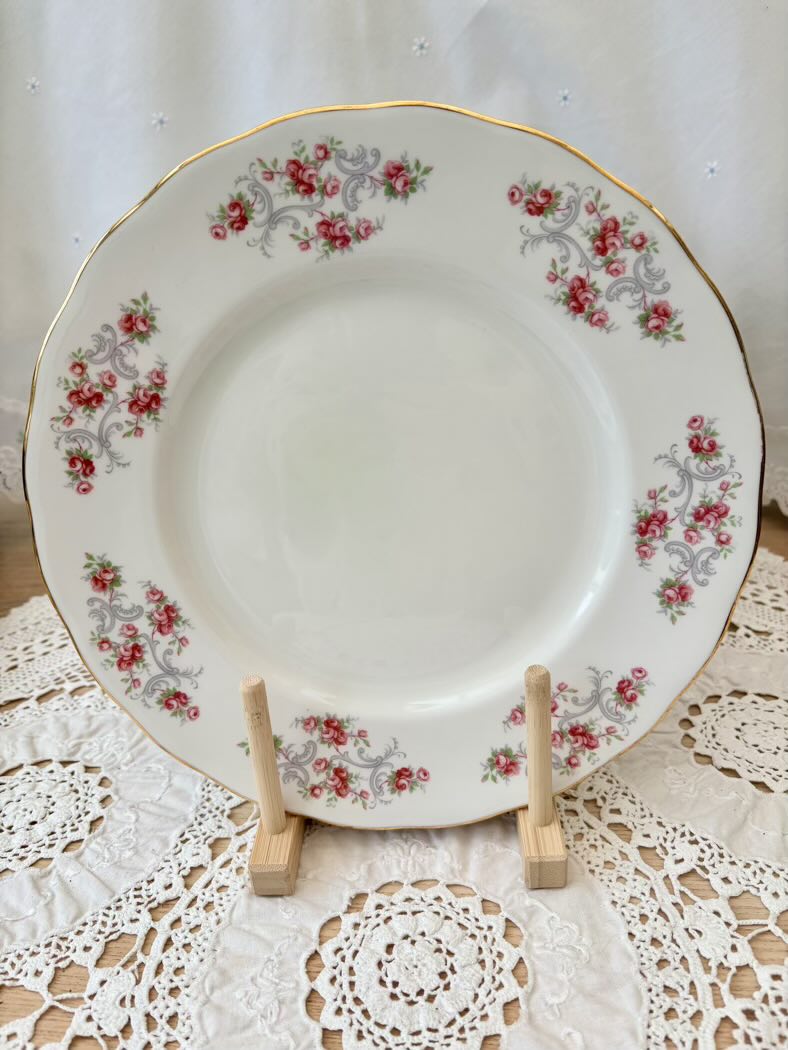 Decorative plate with floral pattern on a stand against a white lace background