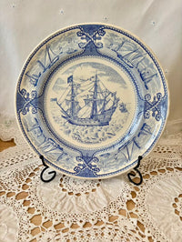 Decorative plate with blue ship design on a lace tablecloth