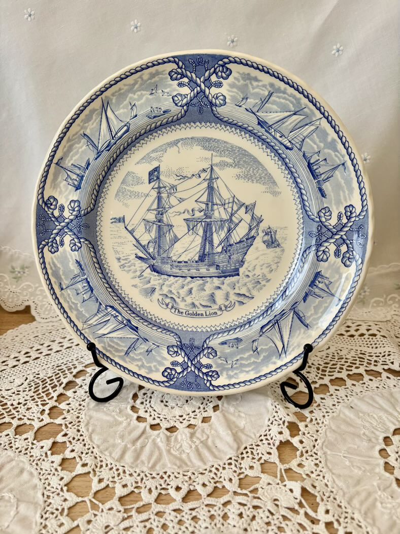 Decorative plate with blue ship design on a lace tablecloth