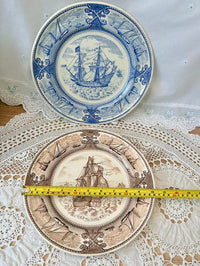 Two decorative plates with ship designs on a lace tablecloth, measured with a tape measure.