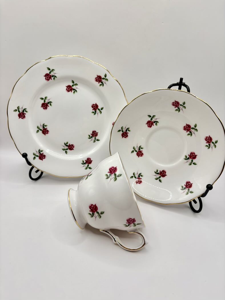 Tea set with a cup, saucer, and plate featuring red rose designs on a white background.