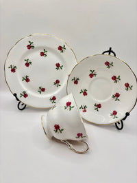 Tea set with a cup, saucer, and plate featuring red rose designs on a white background.