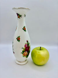 Decorative vase with floral patterns next to a green apple on a white background