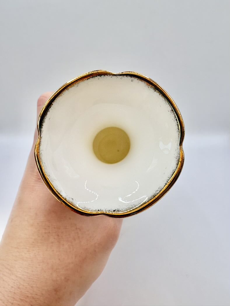 Hand holding a vase against a plain background