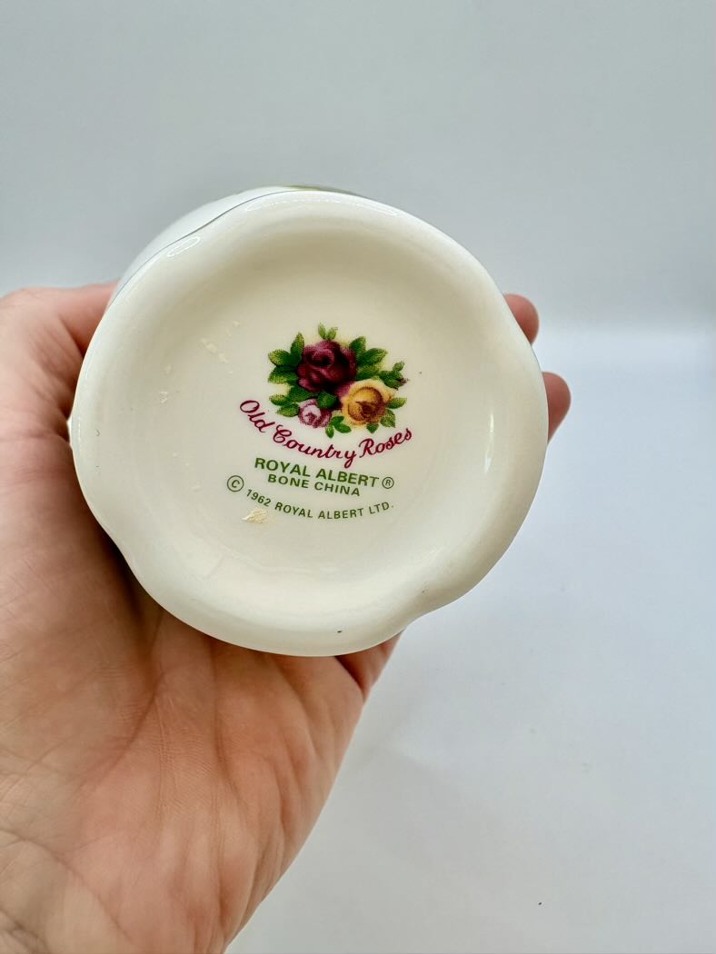 Ceramic dish with 'Old Country Roses' and 'Royal Albert' branding held in a hand against a light background.