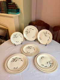 Set of ceramic plates with floral design on a table in a room with a fireplace and chairs.