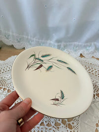 Hand holding a decorative plate with floral design on a lace tablecloth.