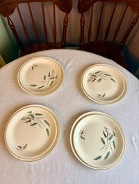 Four ceramic plates with decorative patterns on a tablecloth.