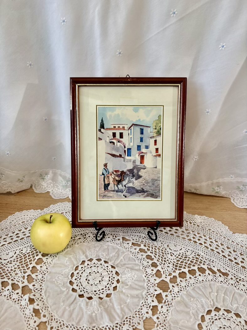 Framed artwork on a lace tablecloth with an apple beside it