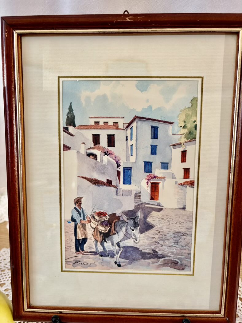 Framed artwork of a village scene with a man and donkey.
