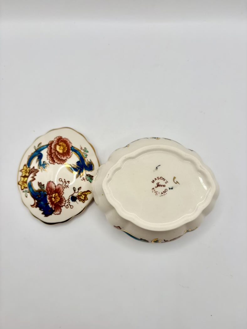 Decorative ceramic box with floral design on lid and text on base against a white background