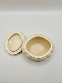 Beige ceramic container with lid on a light gray background