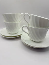 Set of white ceramic cups and saucers on a light gray background