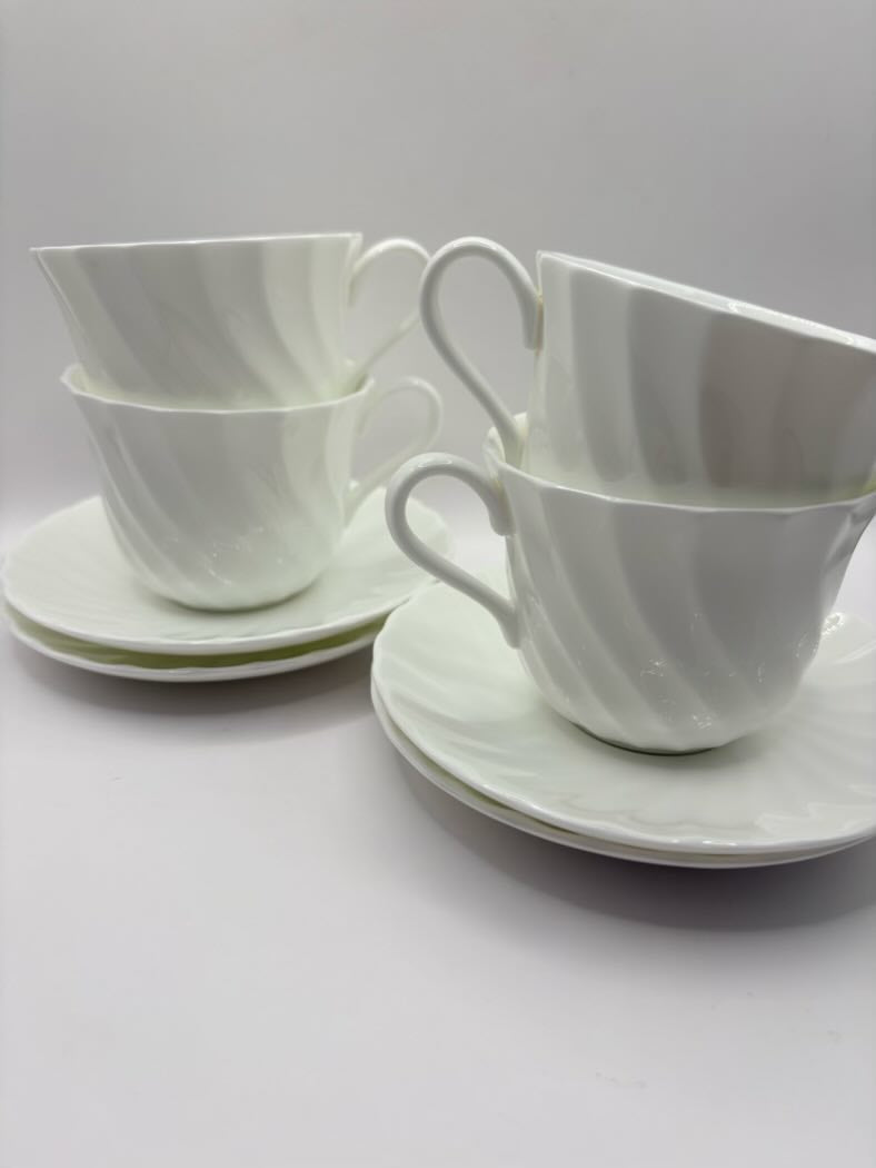 Set of white ceramic cups and saucers on a light gray background