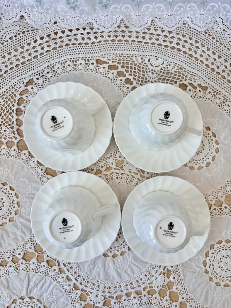 Four white ceramic cups with black logos on a lace tablecloth