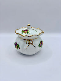 Decorative ceramic lidded container with floral designs on a white background