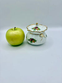 Green apple next to a decorative ceramic pot on a light gray background