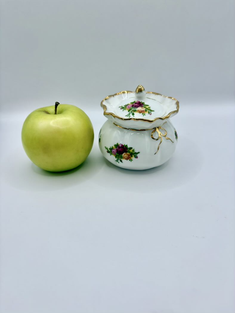 Green apple next to a decorative ceramic pot on a light gray background