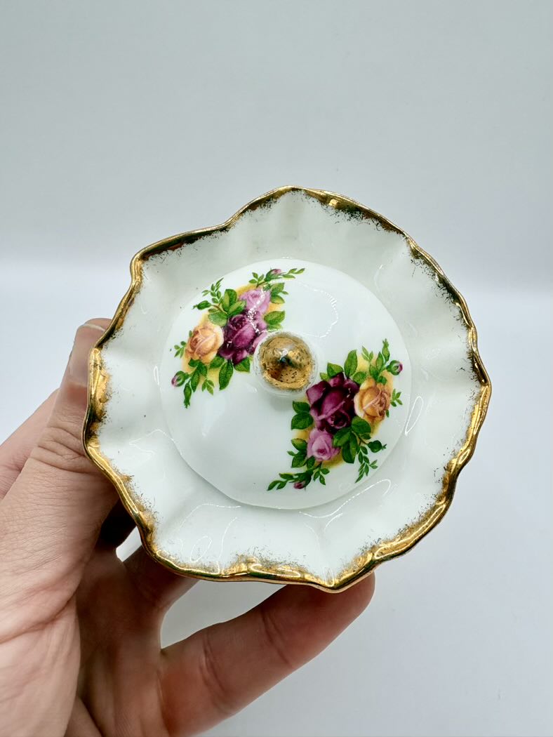 Decorative ceramic dish with floral design held by a hand on a plain background