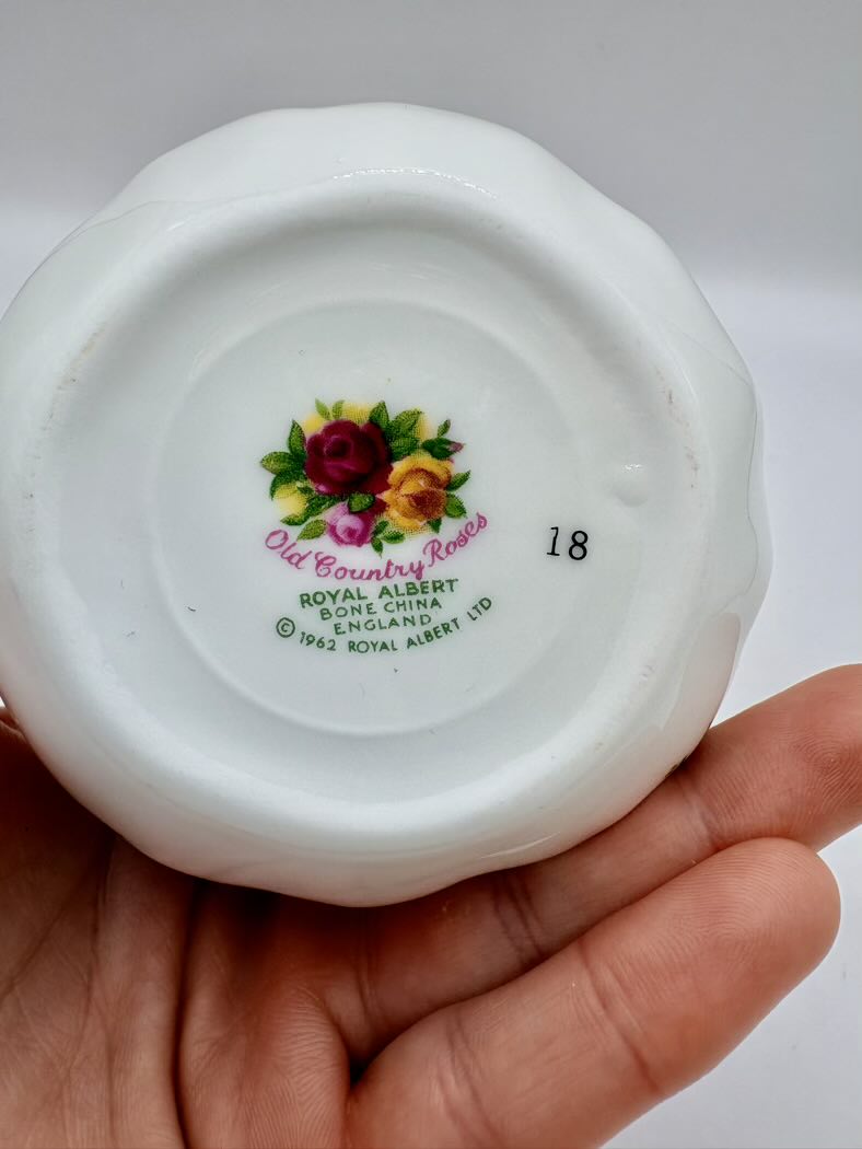 White ceramic item with floral design and 'Old Country Roses' branding held in a hand against a white background.